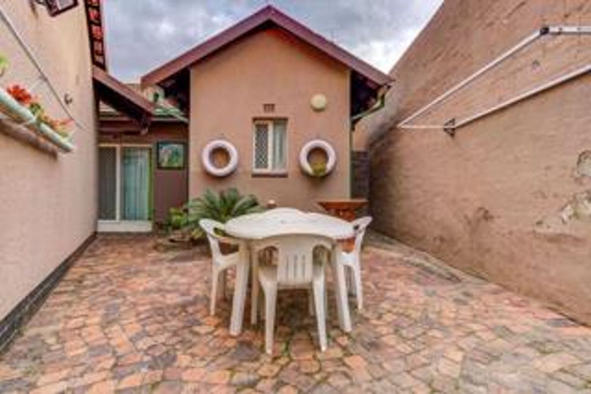 A paved rear courtyard area featuring a sliding glass door entrance and a wall-mounted clothesline, providing a functional outdoor space.