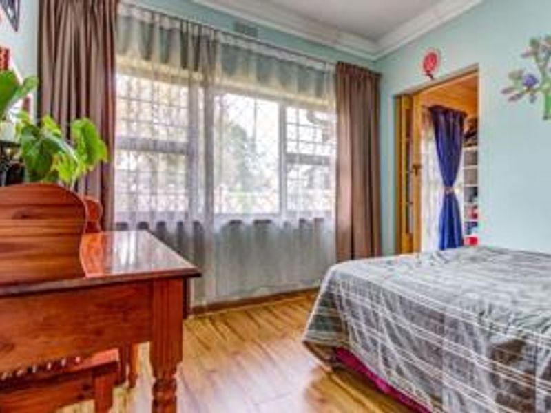 A bedroom featuring laminate flooring, crown molding, and a large window, with an adjacent built-in closet area.