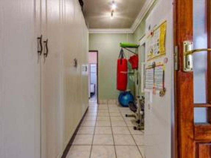A functional hallway featuring extensive built-in storage cupboards, tiled flooring, and classic cornicing, providing a practical transition space within the home.