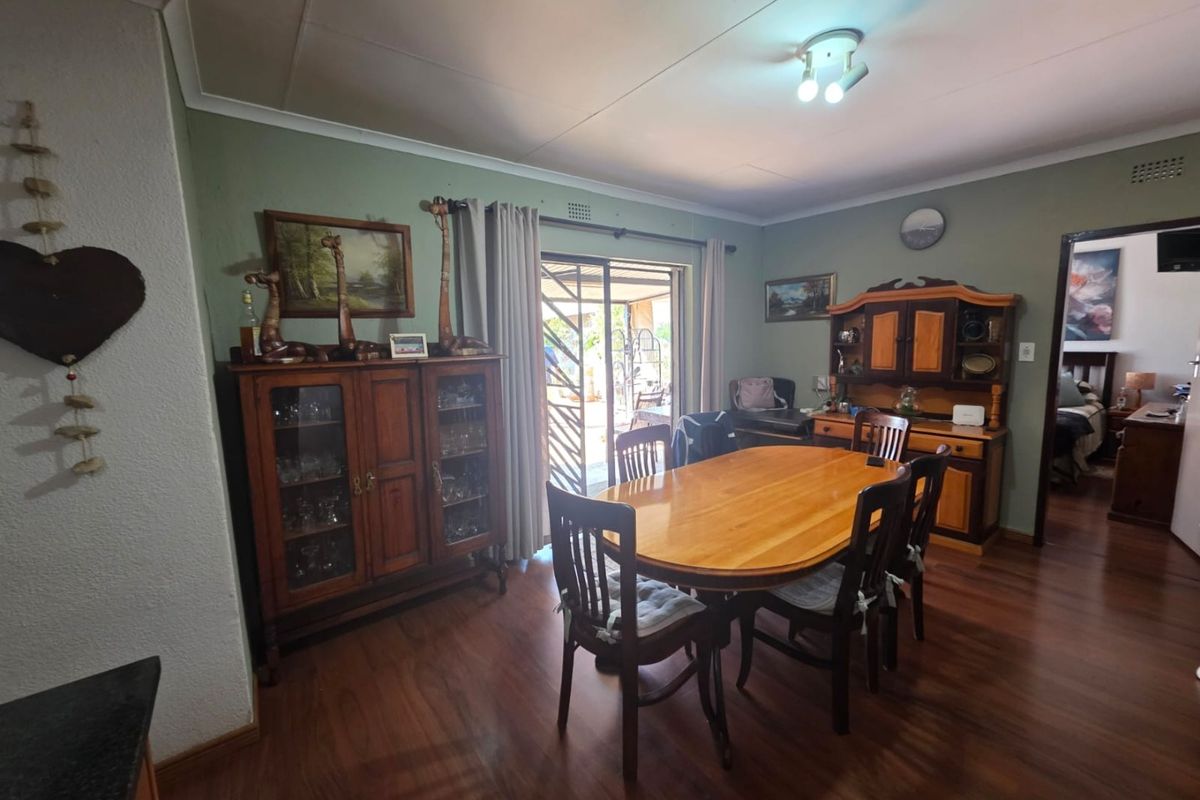 A dining room featuring wood-look flooring, coved ceilings, and a sliding glass door providing access to the outdoor patio area.