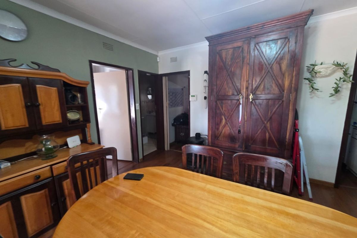 A dining area featuring wooden flooring and access to adjacent rooms, providing a functional space for family meals.