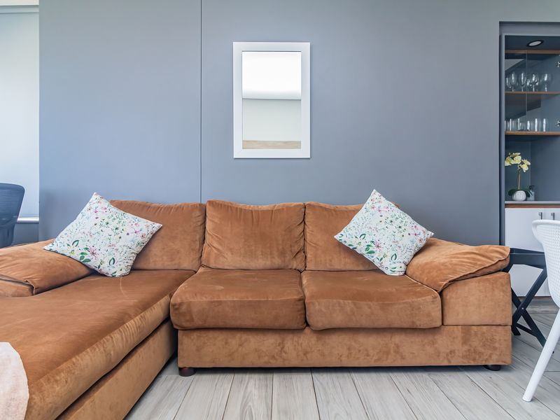 A well-maintained living area featuring a neutral grey feature wall, light-toned laminate flooring, and a convenient built-in display cabinet.