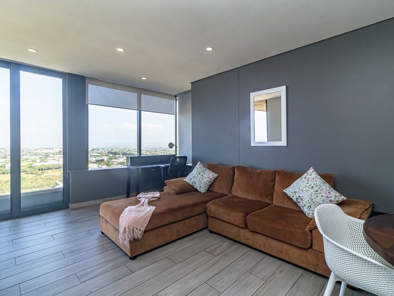Modern living area featuring wood-look tile flooring, recessed lighting, and expansive floor-to-ceiling windows offering panoramic views.