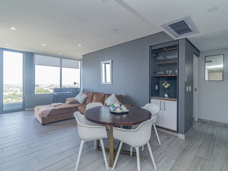 Modern open-plan living and dining area featuring large windows with panoramic views, recessed lighting, ducted air conditioning, and sleek built-in cabinetry.