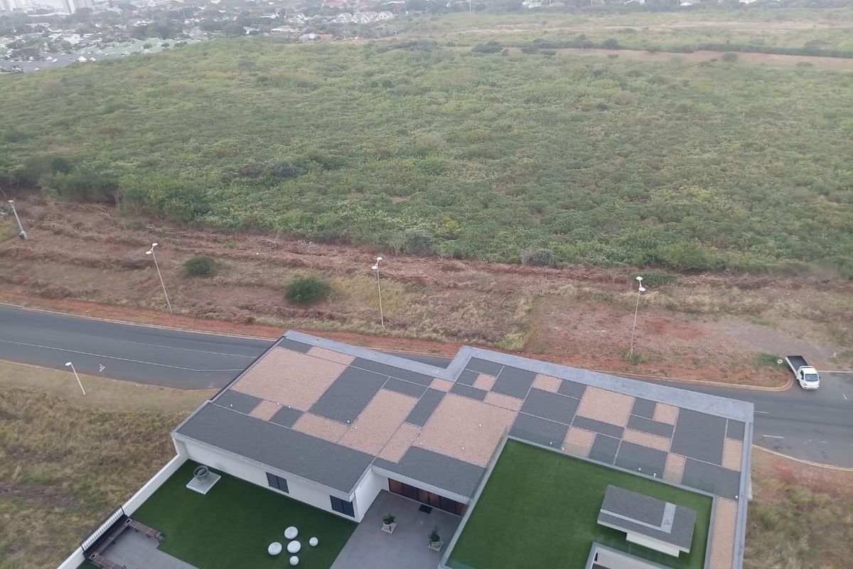 An elevated aerial view of the property showing the modern roof design, landscaped rooftop areas, and surrounding coastal landscape.