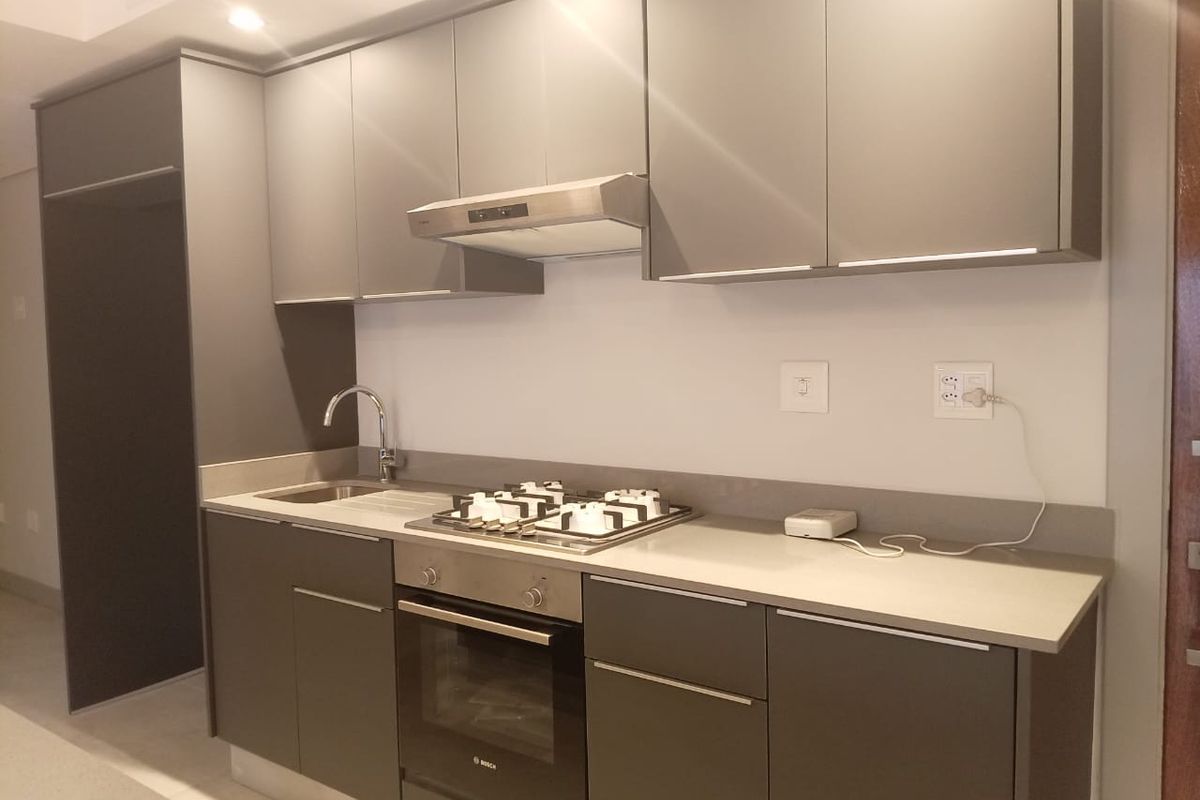Modern kitchen featuring sleek grey cabinetry, stone countertops, a built-in Bosch oven, gas hob, and stainless steel extractor fan.