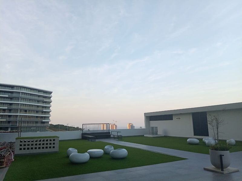 A modern rooftop terrace featuring artificial turf, paved walkways, and a contemporary design, offering an open-air space for relaxation and outdoor enjoyment.