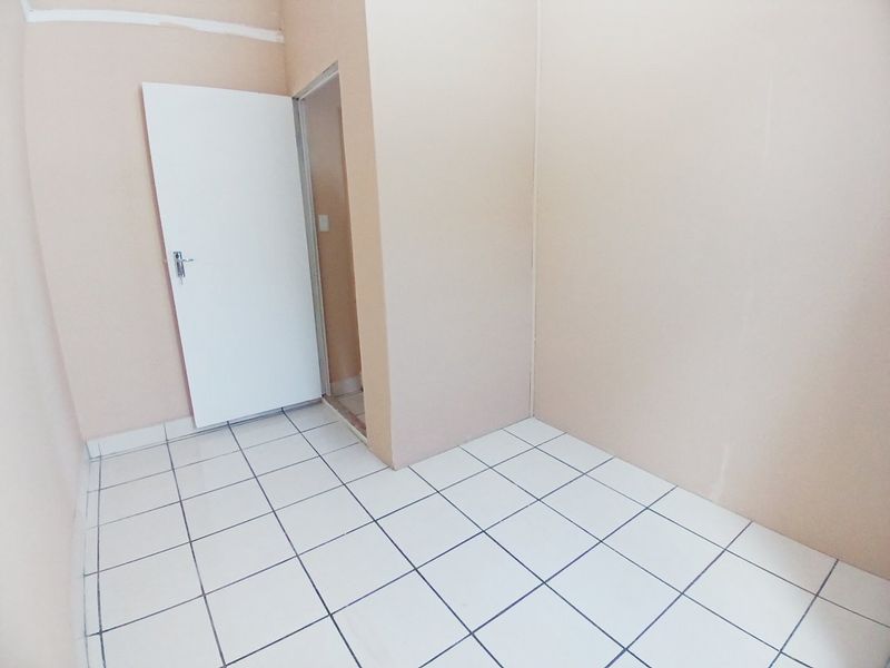 A vacant bedroom featuring white tiled flooring and neutral wall paint, providing a blank canvas for potential interior design updates.