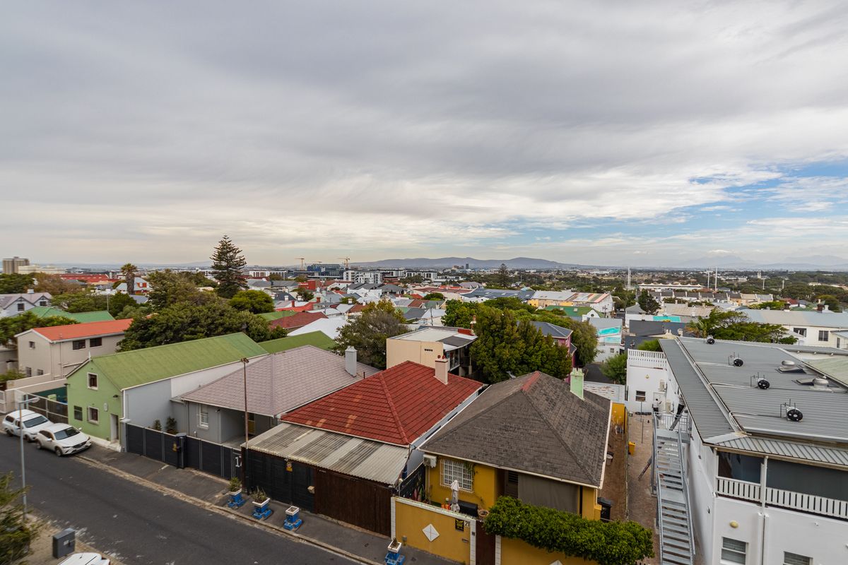 An elevated aerial view overlooking a residential neighborhood with various roof styles and surrounding urban landscape.