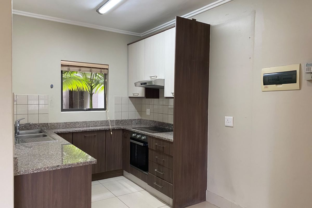 A functional kitchen featuring granite countertops, built-in cabinetry, an integrated oven and hob, and a stainless steel sink.