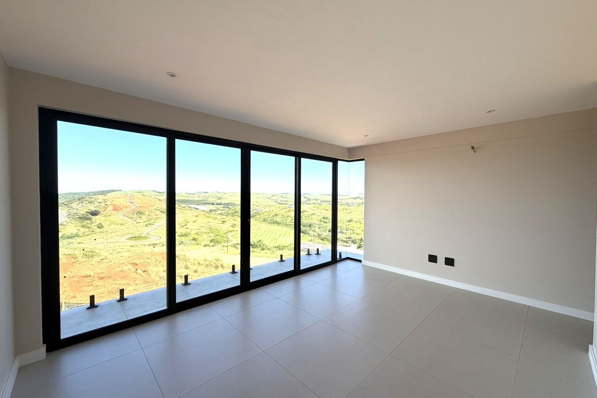 A bright, modern living area featuring large floor-to-ceiling glass sliding doors that offer expansive, unobstructed views of the surrounding landscape.