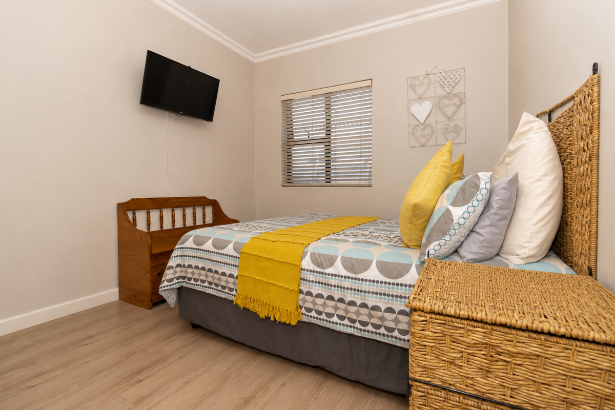 A well-maintained bedroom featuring light wood-look flooring, neutral wall tones, and a window fitted with horizontal blinds.