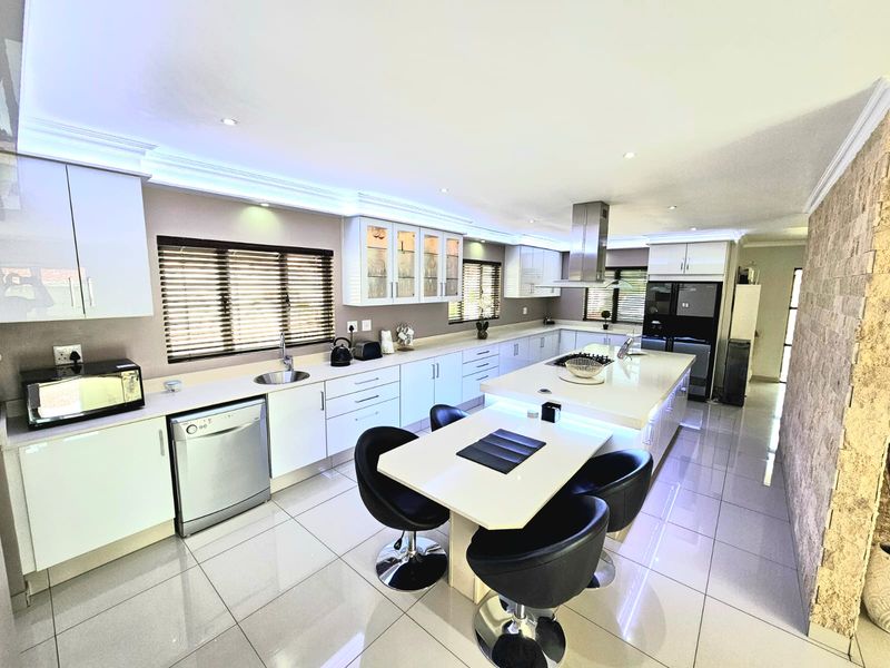 Modern, spacious kitchen featuring a large central island with breakfast bar, sleek cabinetry, integrated appliances, and polished tile flooring.