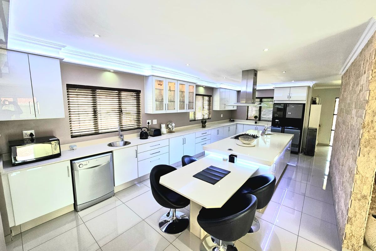 Modern, spacious kitchen featuring a large central island with breakfast bar, sleek cabinetry, integrated appliances, and polished tile flooring.