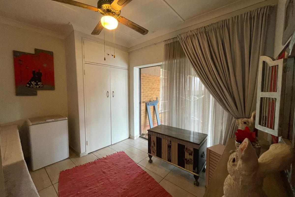 A bedroom featuring built-in cupboards, tiled flooring, a ceiling fan, and direct access to an outdoor area through a sliding glass door.