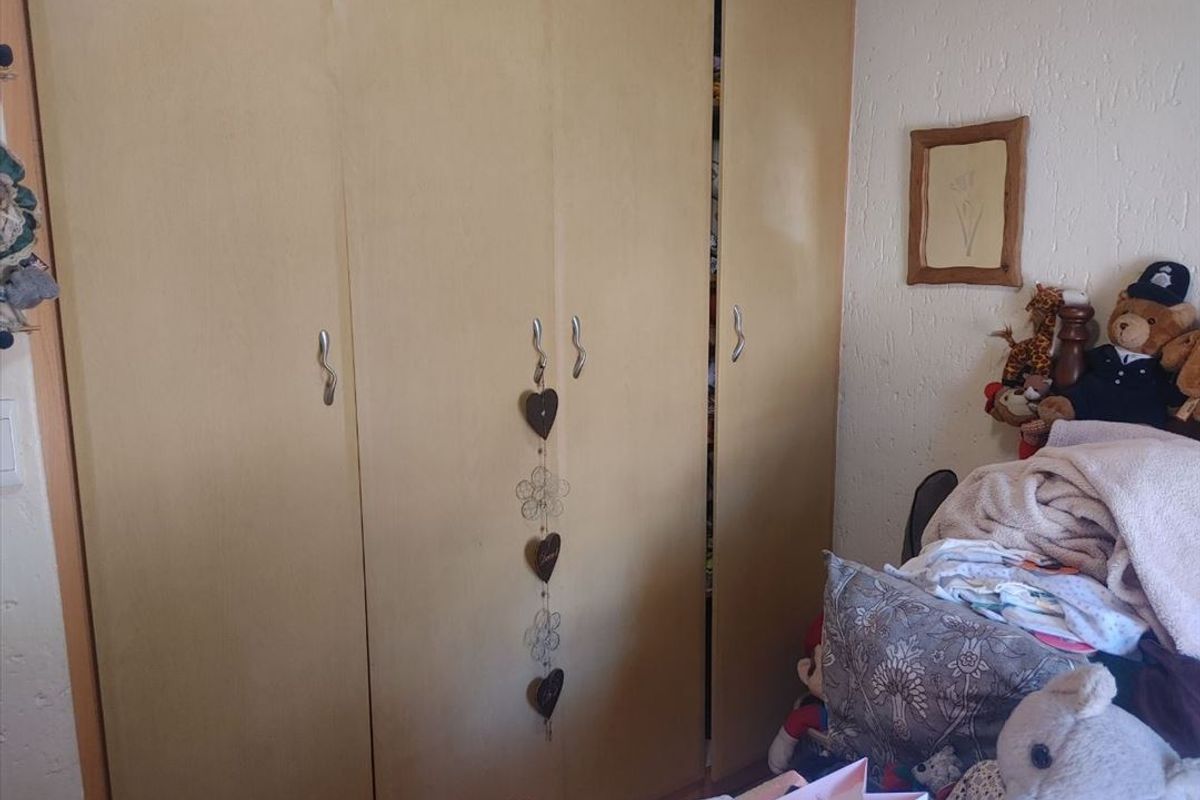 A bedroom featuring built-in wooden cupboards with integrated handles.