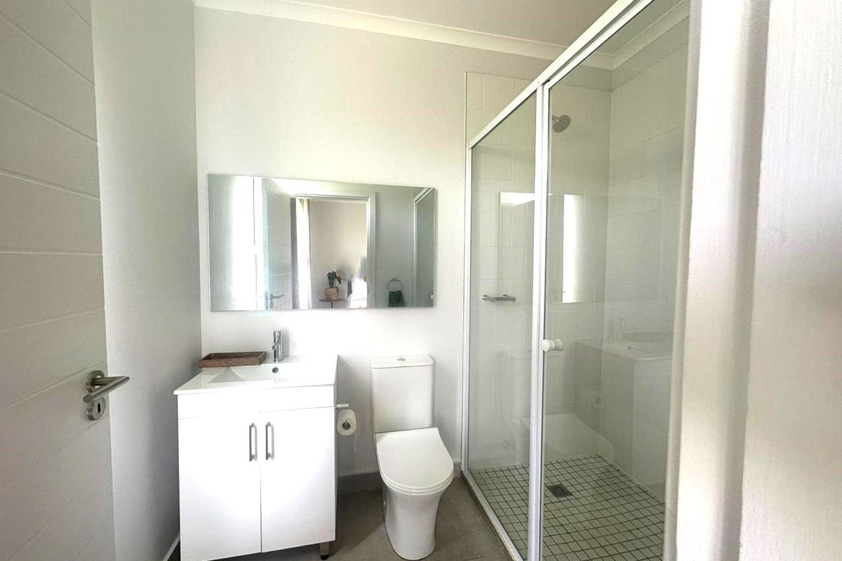 A clean and modern bathroom featuring a white vanity, a glass-enclosed shower, and a wall-mounted mirror.