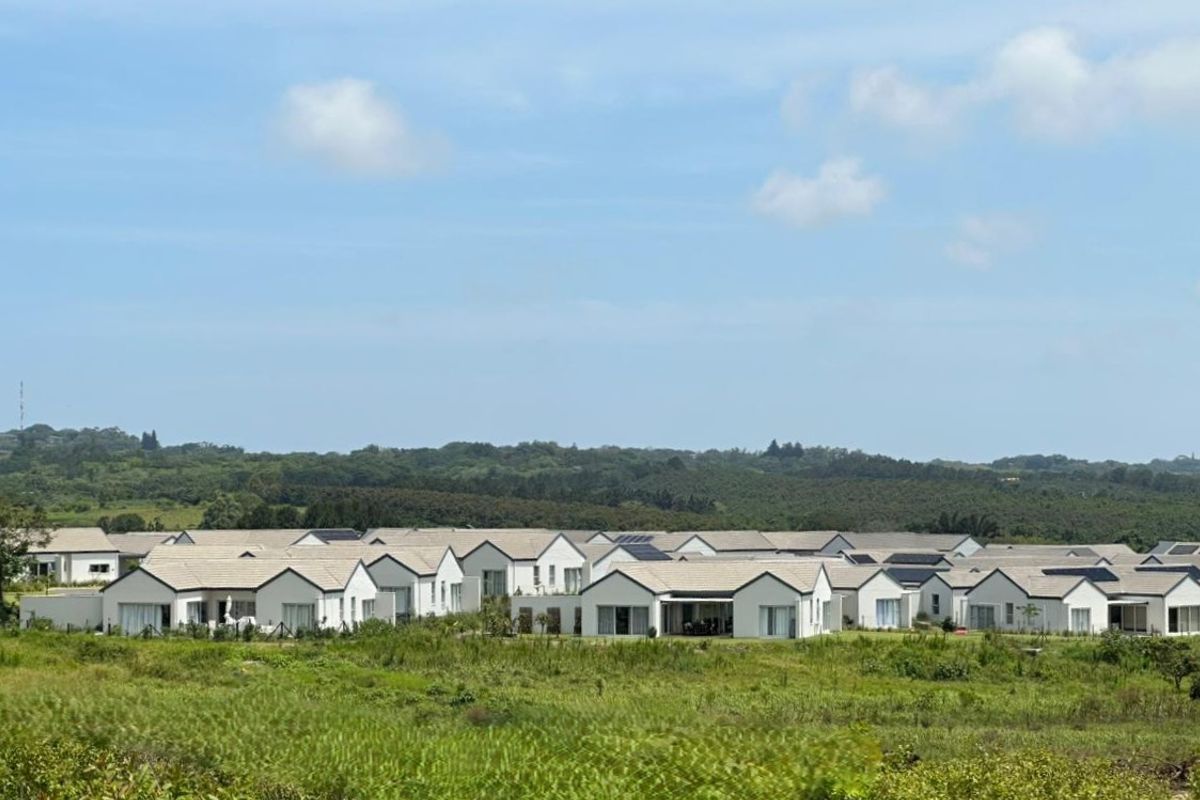 An elevated view of a residential estate featuring multiple modern homes with tiled roofs and integrated solar panels set within a landscaped environment.