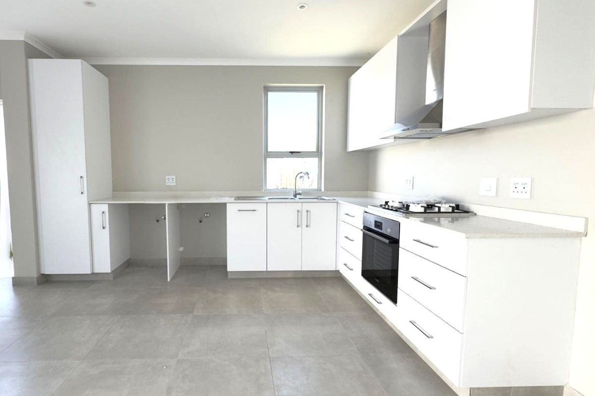 Modern kitchen featuring white cabinetry, stone countertops, built-in oven, gas hob, and tiled flooring in a clean, minimalist design.