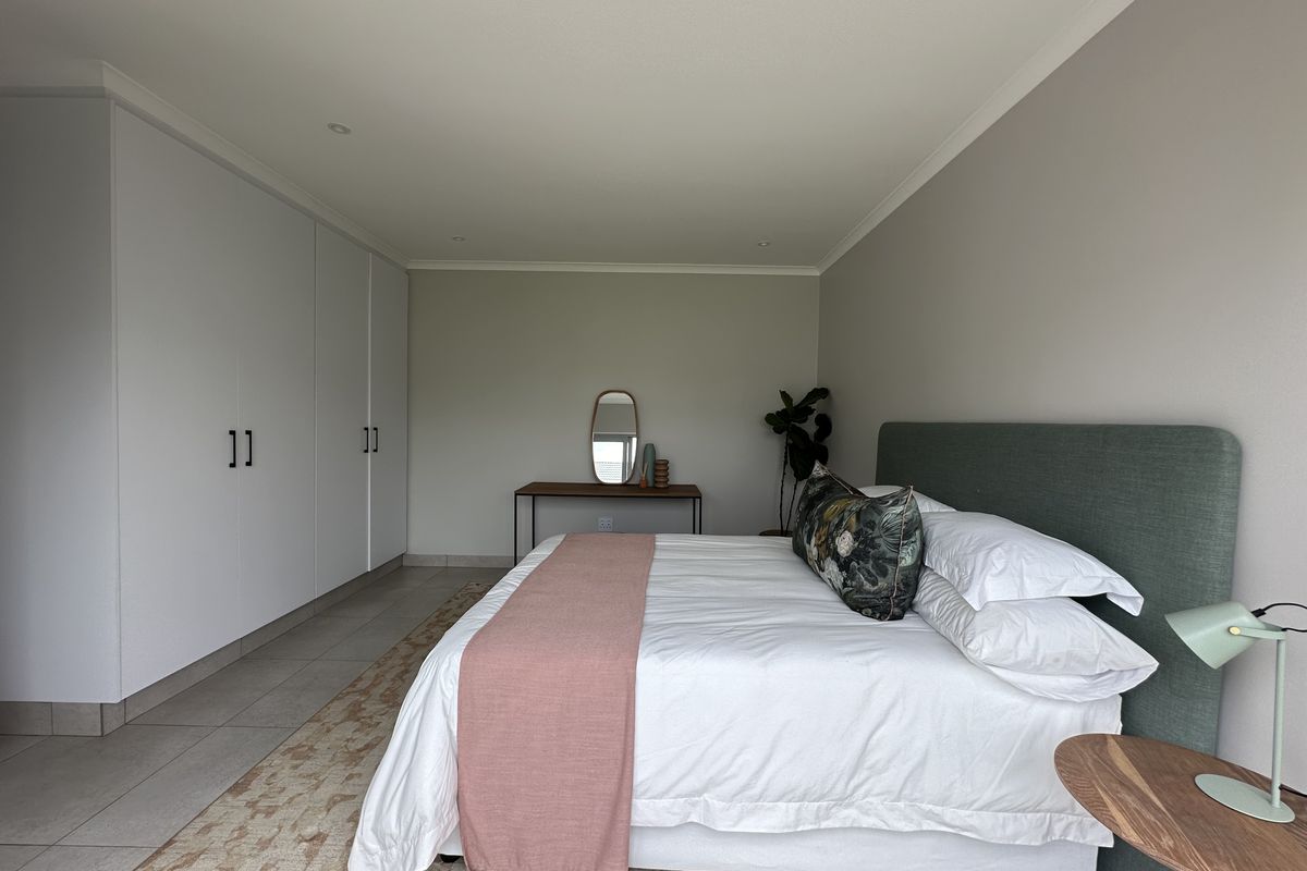 A spacious bedroom featuring neutral walls, tiled flooring, and extensive built-in floor-to-ceiling wardrobes providing ample storage space.
