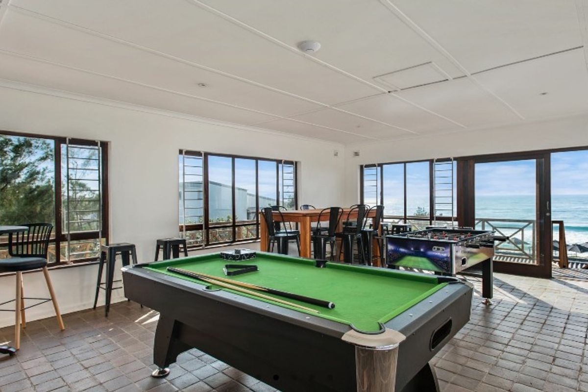 Spacious entertainment area featuring tiled flooring, large windows with ocean views, and direct access to an outdoor balcony.