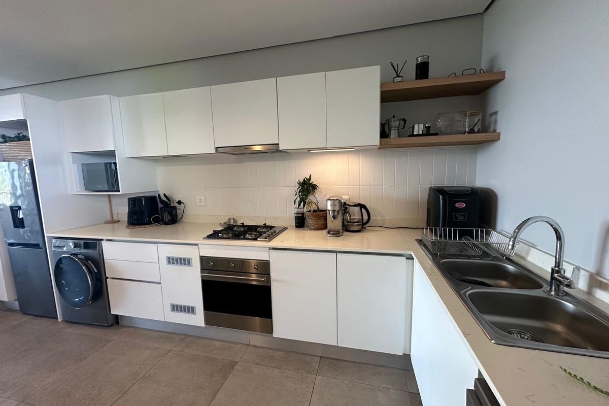 Modern kitchen featuring white cabinetry, stone countertops, integrated stainless steel oven, gas hob, extractor fan, and a double basin sink with tiled splashback.