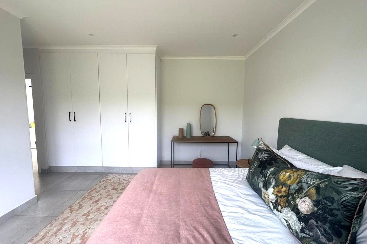 A well-maintained bedroom featuring built-in floor-to-ceiling wardrobes, neutral tiled flooring, and recessed ceiling lighting.