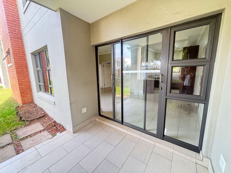 A covered patio area featuring tiled flooring and large sliding glass doors providing access to the interior living space.