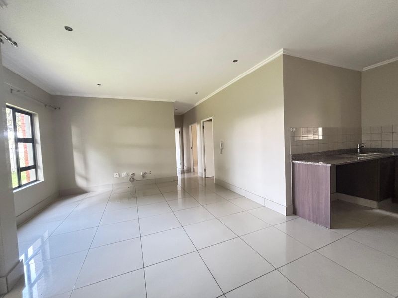Open-plan living area featuring tiled flooring, recessed lighting, and a compact kitchen corner with granite countertops and built-in cabinetry.