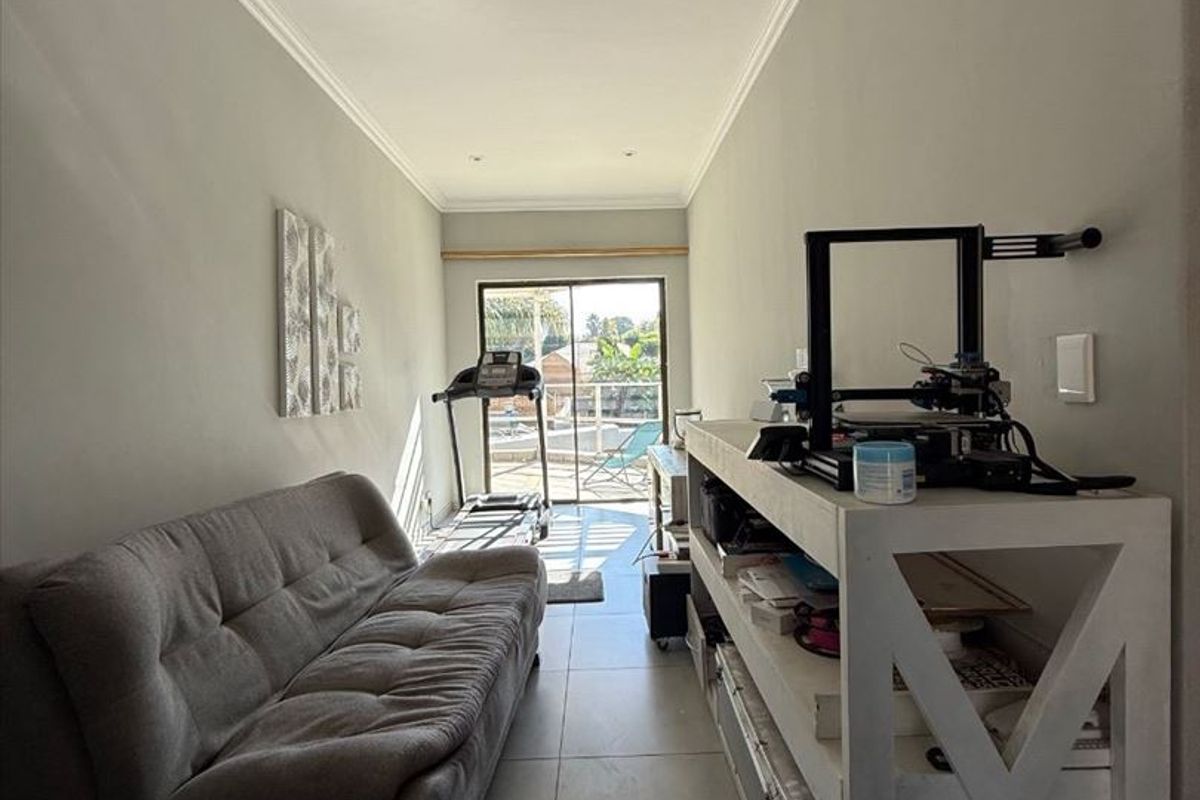 A narrow multi-purpose room featuring tiled flooring, recessed ceiling lighting, and sliding glass doors providing access to an outdoor area.