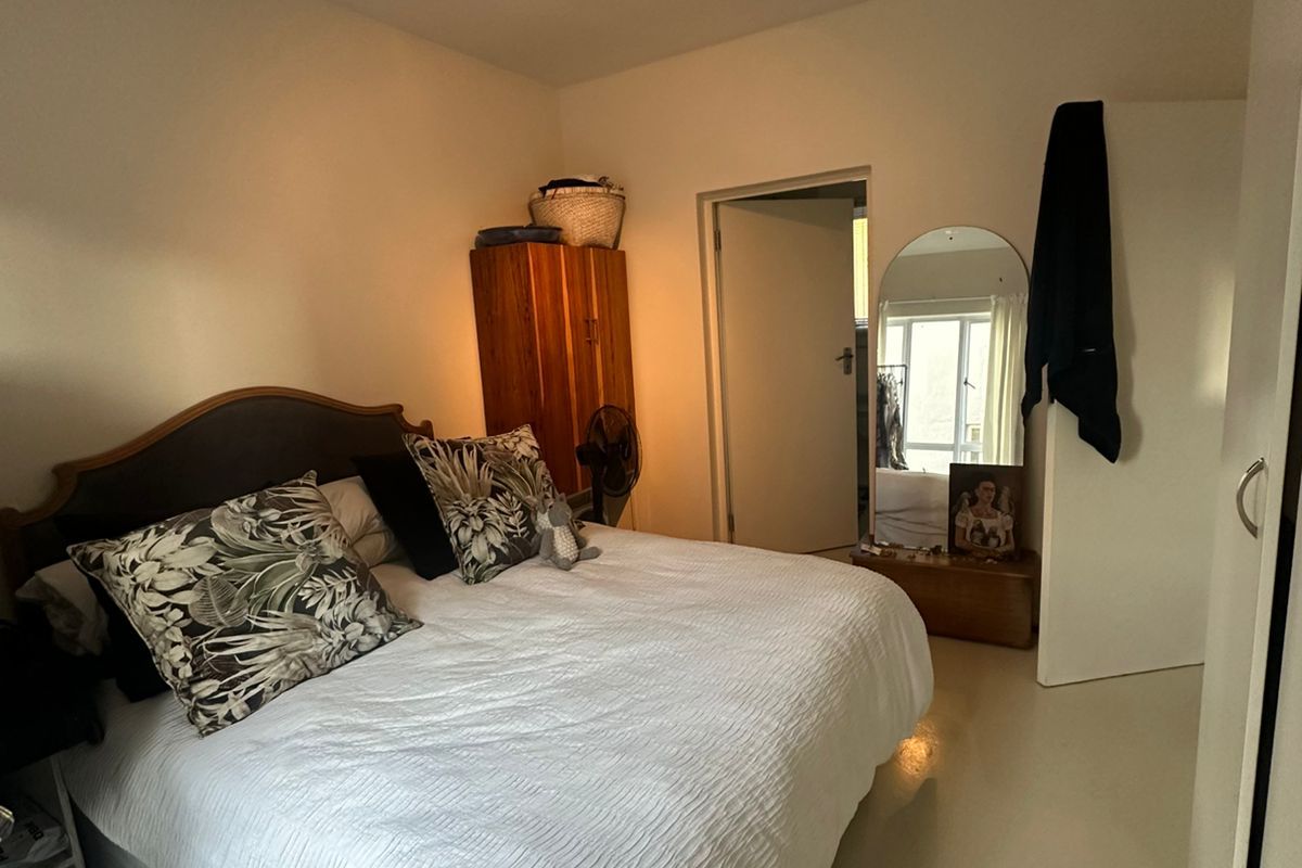 A bedroom featuring neutral flooring, a ceiling-mounted light fixture, and a doorway leading to an adjacent space.