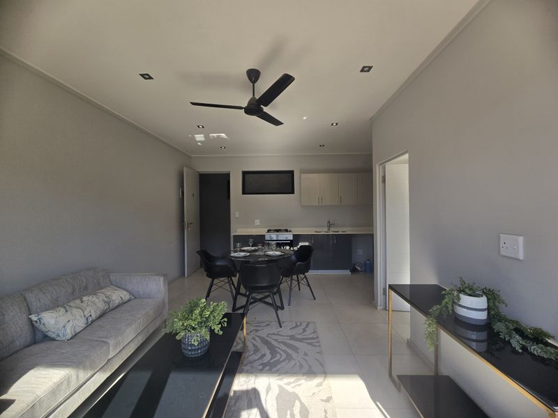 Open plan living and kitchen area featuring modern cabinetry, integrated hob, ceiling fan, and recessed lighting in a neutral, well-maintained space.