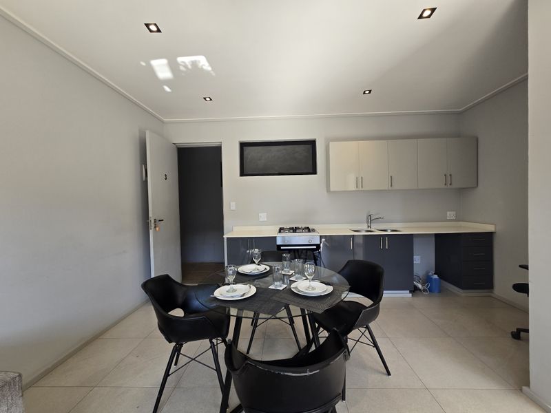 Open plan kitchen and dining area featuring modern cabinetry, a built-in gas hob, stainless steel sink, and tiled flooring.