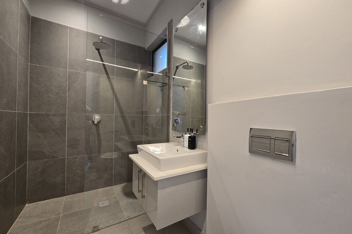 Modern bathroom featuring a walk-in shower with glass screen, wall-mounted vanity with basin, and a concealed cistern toilet.