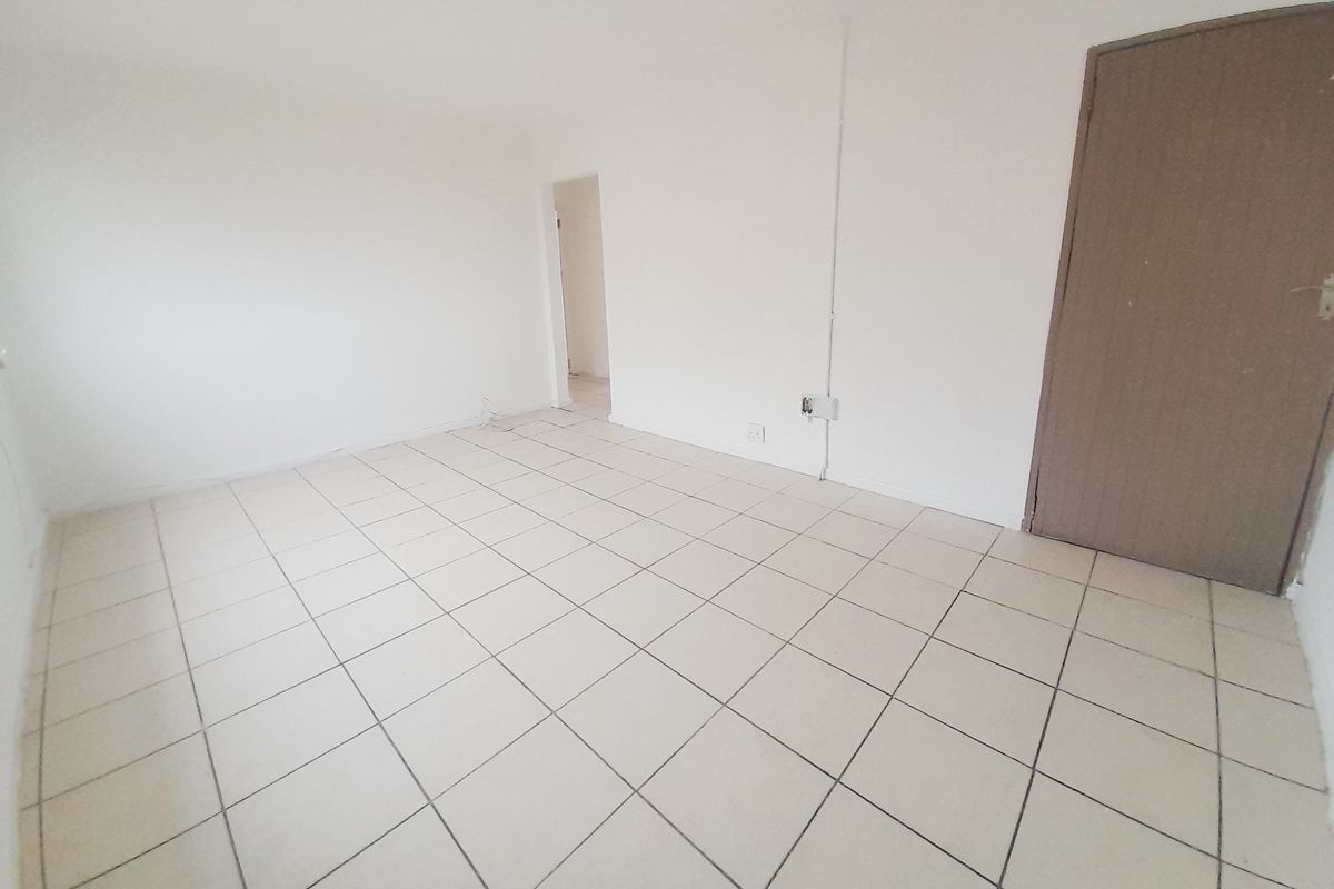An empty, neutrally finished room featuring tiled flooring and a single interior door, providing a blank canvas for potential renovation or interior design.