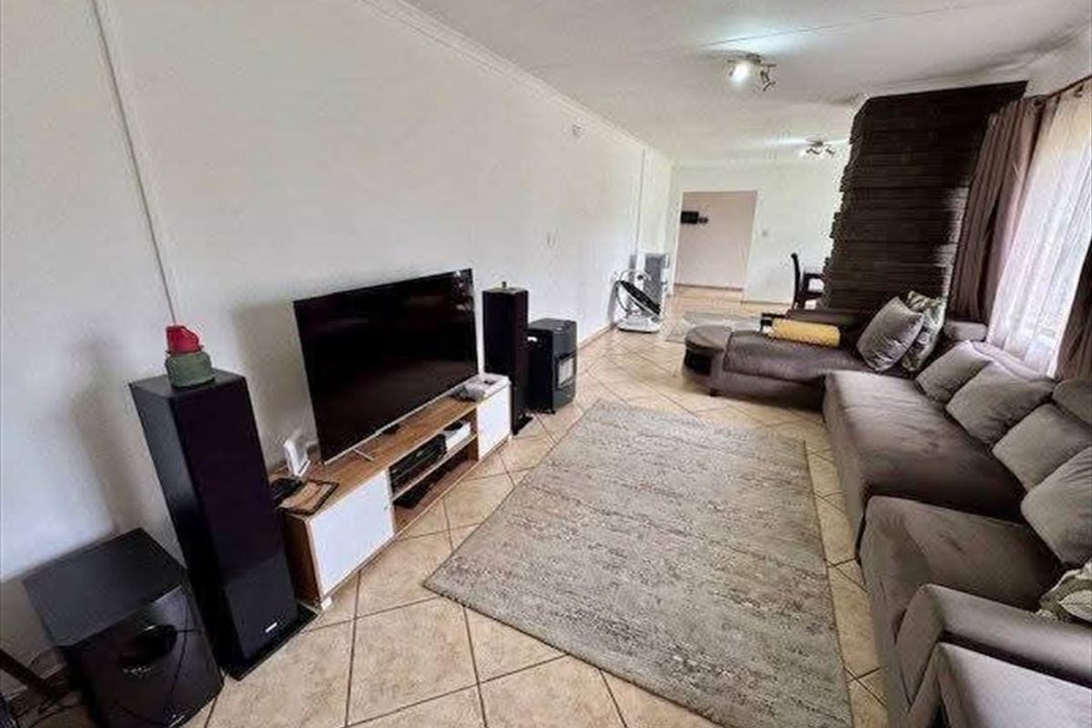 Spacious living room featuring tiled flooring and a prominent stone-clad feature wall, offering a comfortable and functional layout.