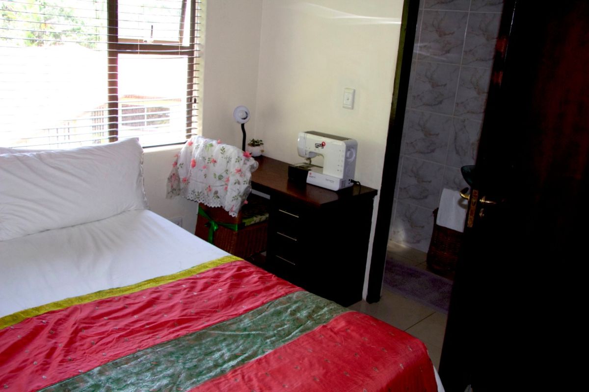 A bedroom featuring a window with blinds and an en-suite bathroom with tiled walls.