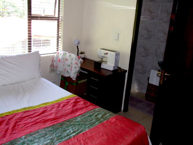 A bedroom featuring a window with blinds and an en-suite bathroom with tiled walls.