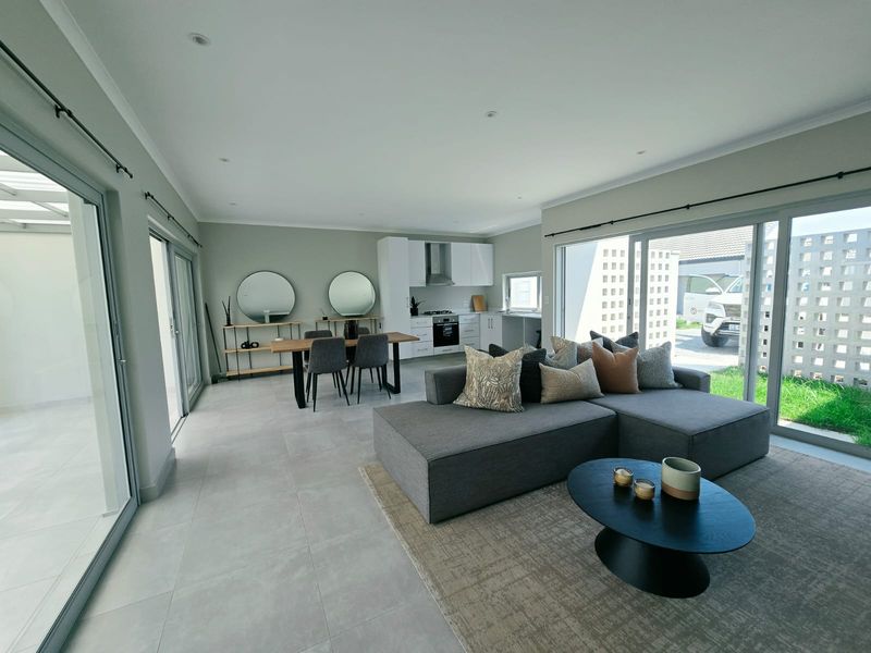 Spacious open-plan living and kitchen area featuring modern cabinetry, integrated appliances, tiled floors, and large sliding doors providing seamless access to the outdoor space.