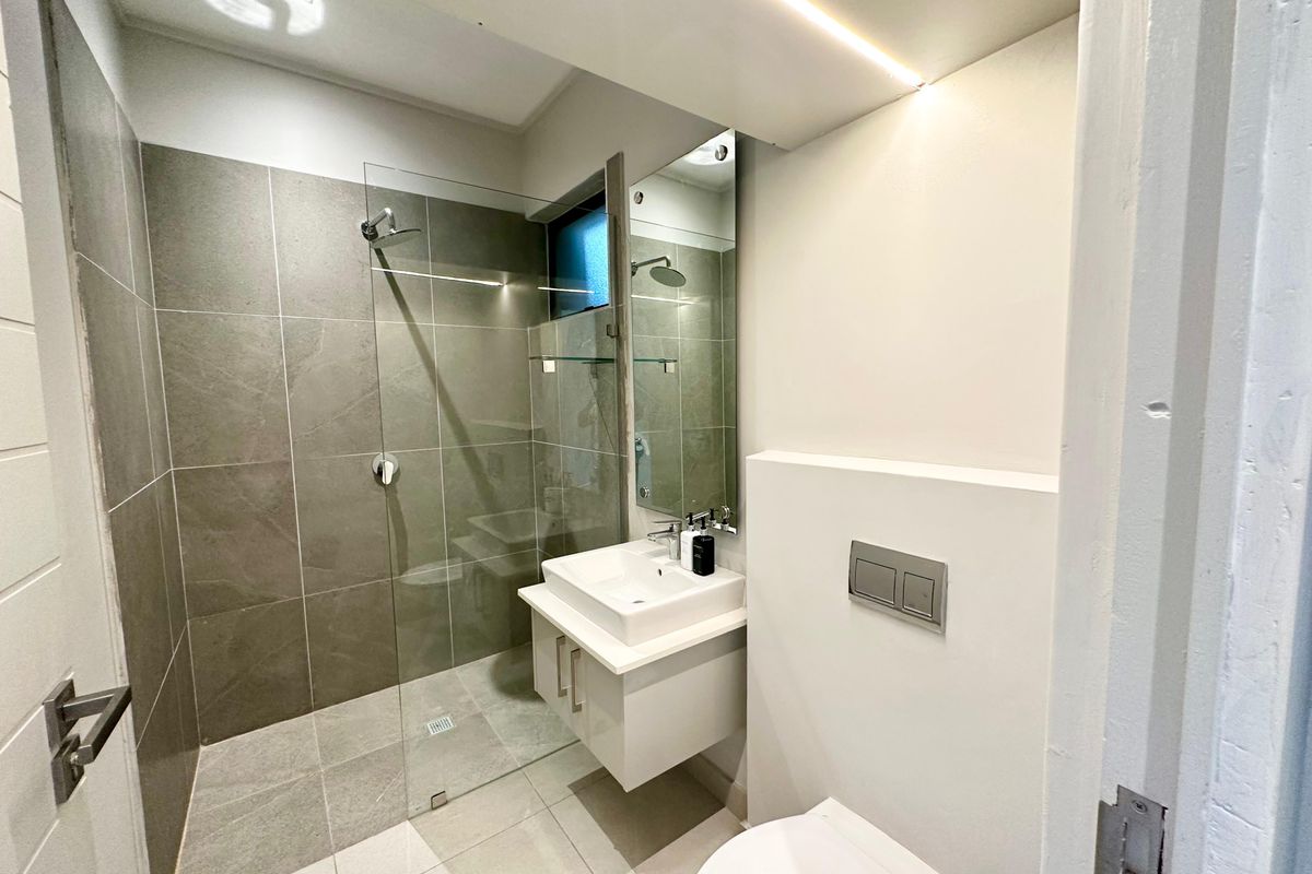 Modern bathroom featuring a walk-in shower with glass screen, wall-mounted vanity with basin, and a concealed cistern toilet.