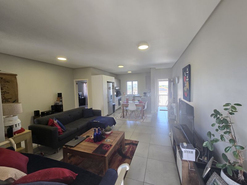 Open plan living and dining area featuring tiled flooring, recessed ceiling lighting, and a functional kitchen layout with access to a balcony.