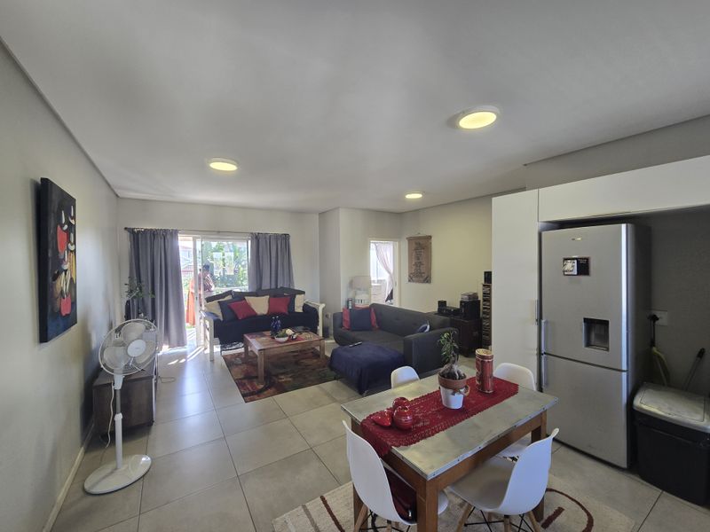 Open-plan living and dining area featuring tiled flooring, recessed ceiling lighting, and direct access to an outdoor balcony through sliding glass doors.