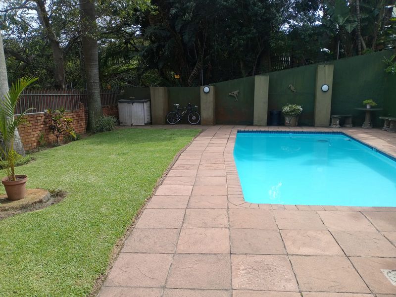 Private outdoor pool area featuring a paved surround, established lawn, and perimeter boundary walls with integrated lighting.