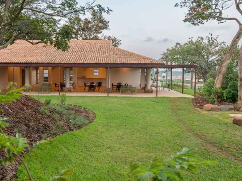 A view of the rear exterior featuring a spacious covered patio with a terracotta tile roof, overlooking a well-maintained landscaped garden.