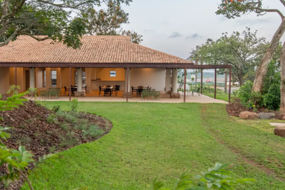 A view of the rear exterior featuring a spacious covered patio with a terracotta tile roof, overlooking a well-maintained landscaped garden.