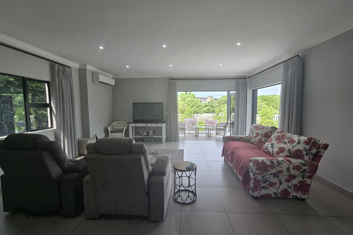 Spacious living room featuring neutral tiled flooring, recessed downlighting, and large sliding glass doors that provide seamless access to the outdoor patio area.