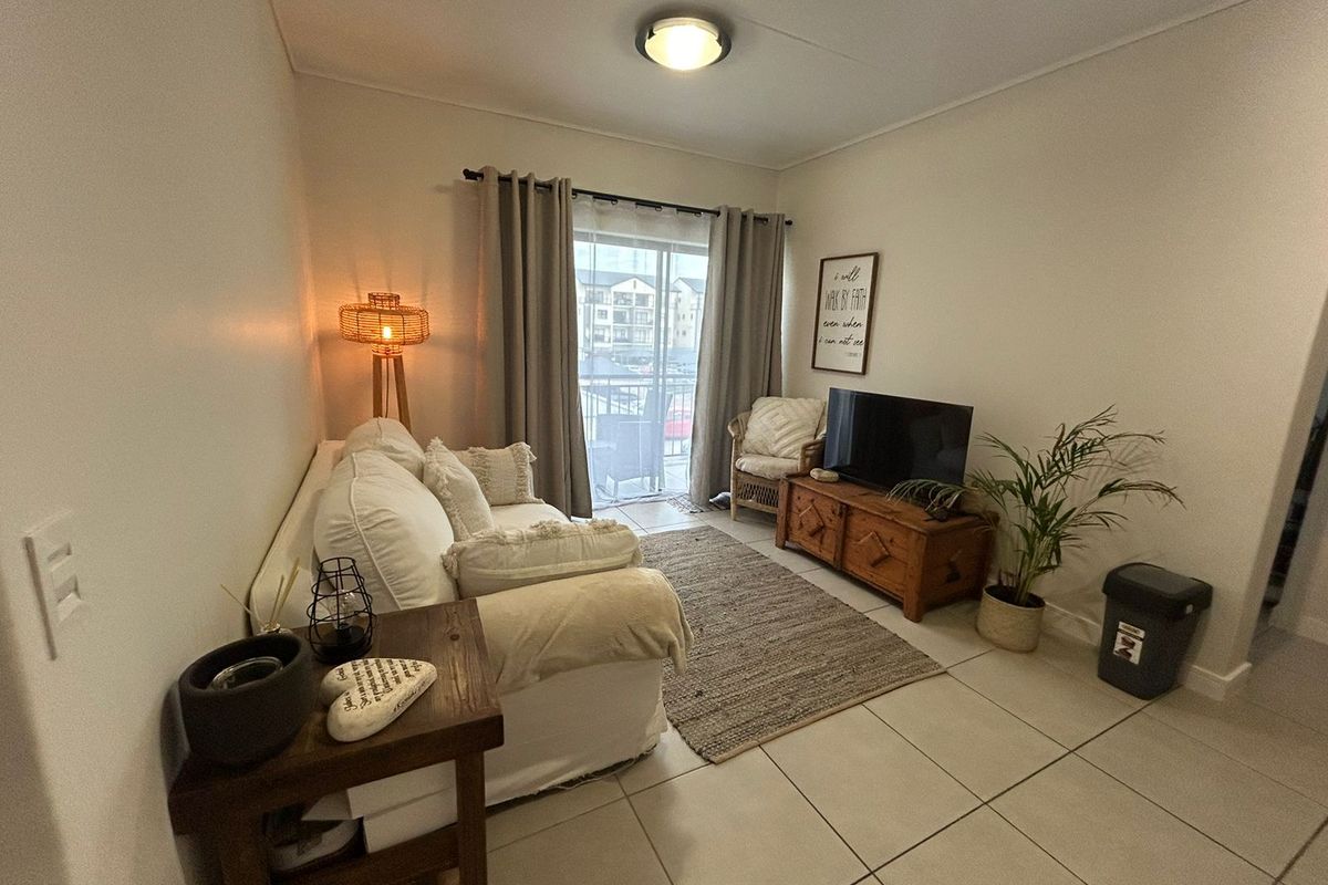 A cozy living room featuring tiled flooring and a sliding glass door that provides access to an outdoor balcony area.