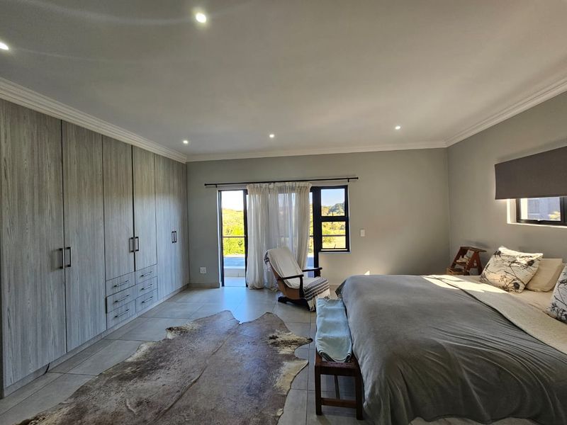 Spacious bedroom featuring extensive built-in cupboards, tiled flooring, recessed lighting, and direct access to an outdoor area through a sliding door.