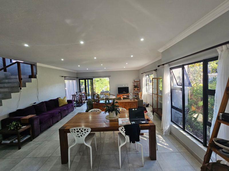 Spacious open-plan living and dining area featuring tiled floors, recessed lighting, and large windows providing ample natural light and garden views.