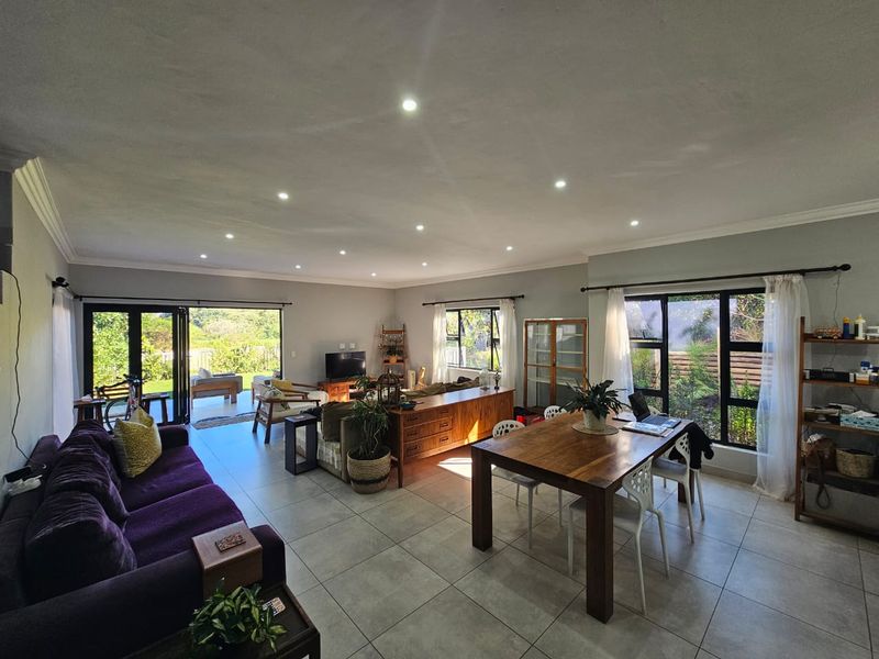 Spacious open-plan living and dining area featuring large aluminium windows and sliding doors that provide abundant natural light and seamless access to the outdoors.